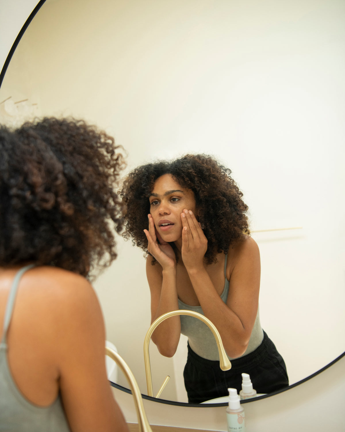 Woman checking her skin in a bathroom mirror