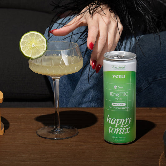 Green Happy Tonix lime can (10mg THC) beside coupe glass with lime slice; hand with red nails reaching