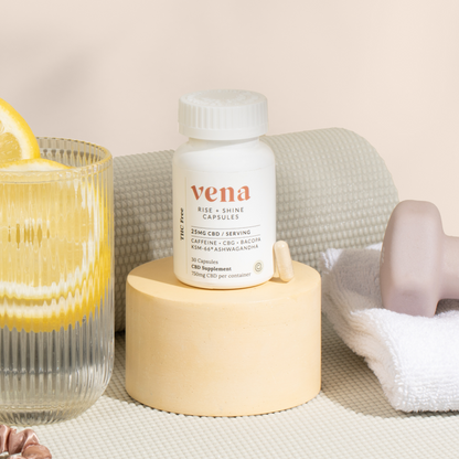 vena RISE + SHINE CAPSULES bottle on a pedestal next to a lemon water glass, towel and soap