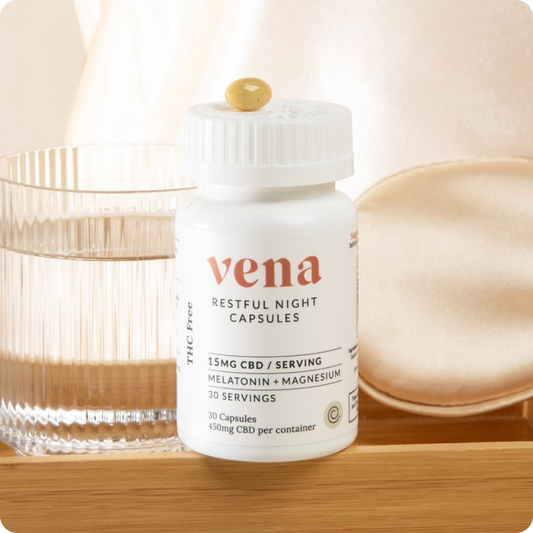 Front view of Restful Night CBD sleep capsules bottle showcasing Vena label and '15 mg CBD per serving' with a glass of water and silk eye mask