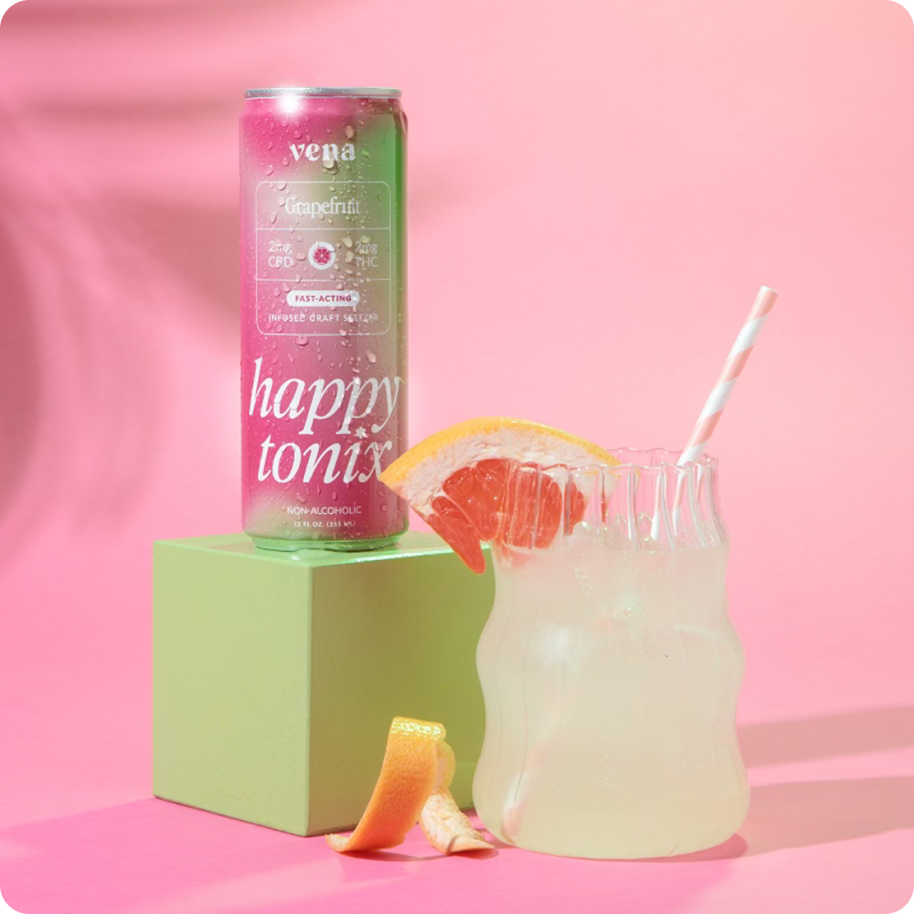 Front view of Vena Happy Tonix Grapefruit seltzer can beside a grapefruit garnished glass on pink background