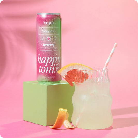 Front view of Vena Happy Tonix Grapefruit seltzer can beside a grapefruit garnished glass on pink background