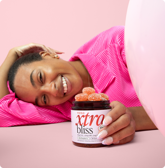 Smiling woman holding jar labeled vena xtra bliss; label reads 10mg THC 10mg CBD 2mg CBN Red Raspberry
