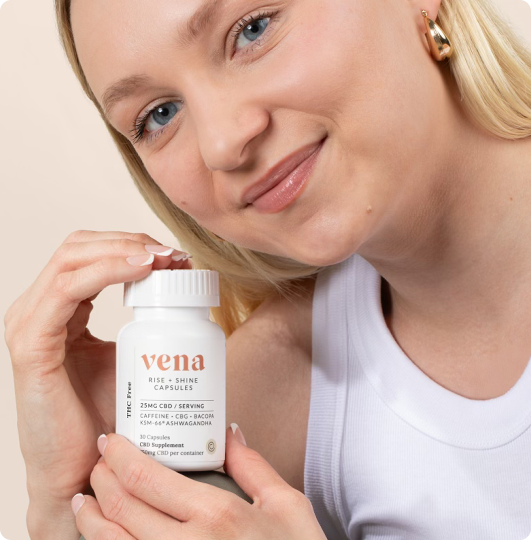 Woman smiling holding a bottle labeled 'vena RISE + SHINE CAPSULES'