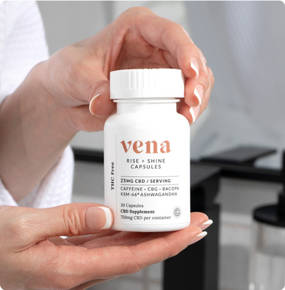 Close-up front view of Rise and Shine CBD bottle showing Vena logo and 25MG CBD per serving label, held in two hands