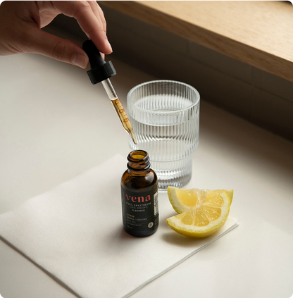 vena CBD tincture bottle with dropper, glass of water and lemon wedges on cloth