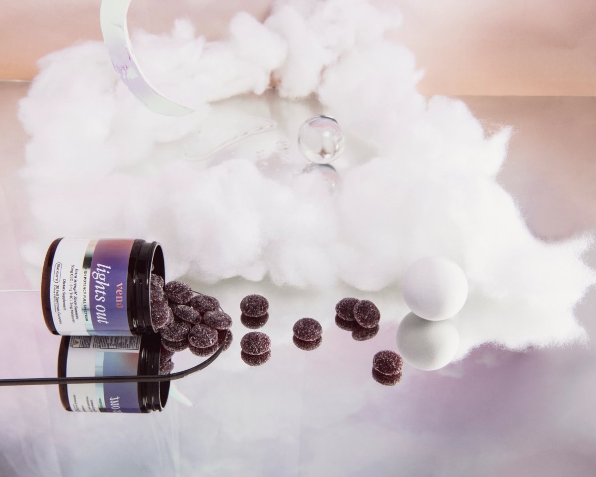 Lights Out gummies spilling from the jar onto a dreamlike cloud set