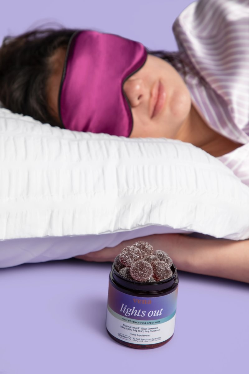 Woman asleep wearing a silk eye mask beside a jar of Lights Out