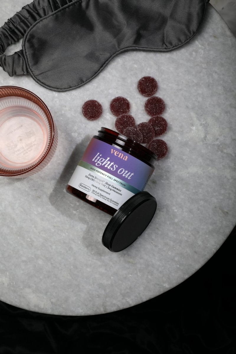 Lights Out jar and gummies on a nightstand with a silk sleep mask