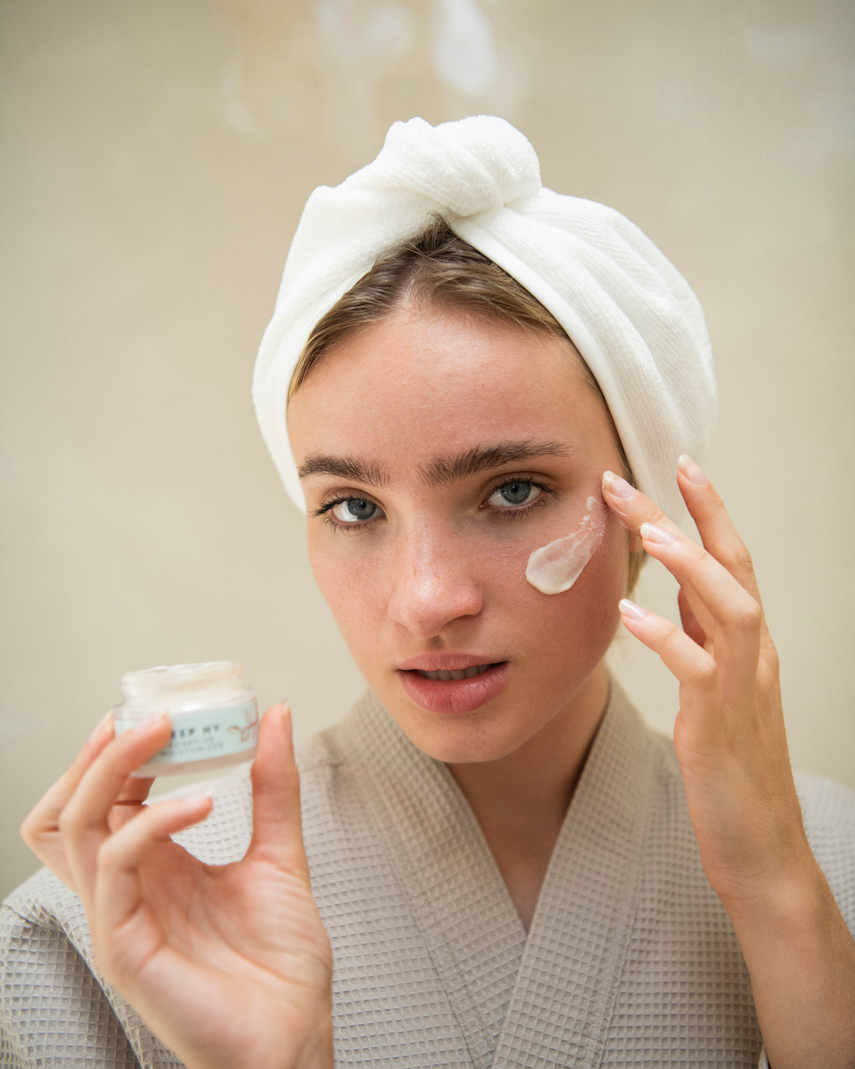 Woman in a towel wrap applying night cream