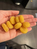 Close-up of hand holding nine yellow puffed corn snacks showing airy puffed texture with stainless sink background
