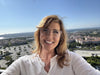Smiling woman on a balcony with coastal city and ocean in the background
